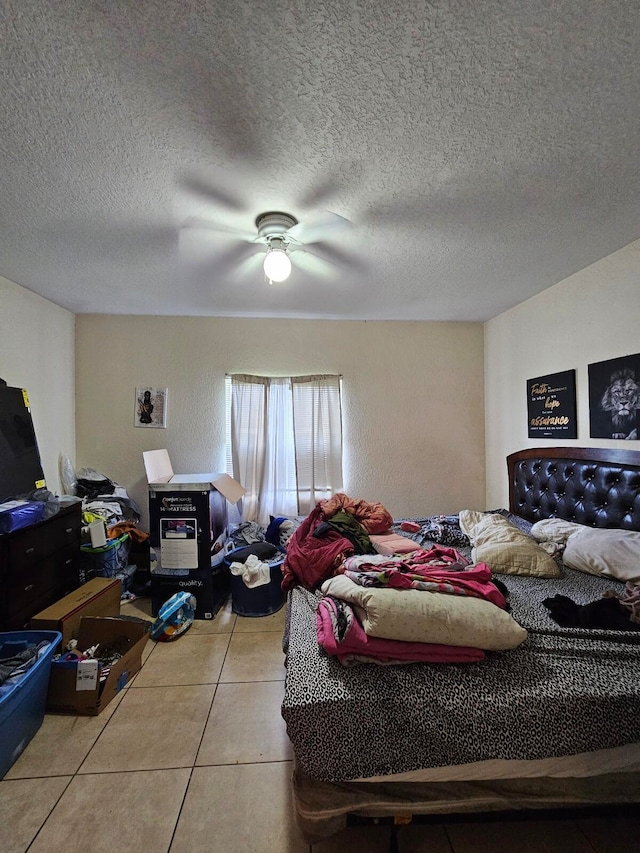 bedroom featuring ceiling fan, light tile patterned floors, and a textured ceiling