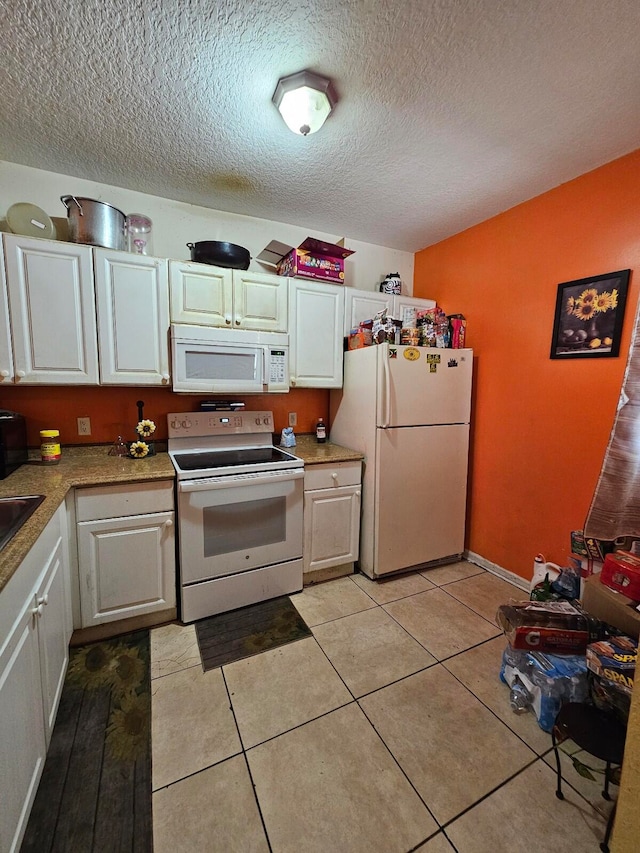 kitchen featuring white appliances, light tile patterned floors, white cabinets, and a textured ceiling