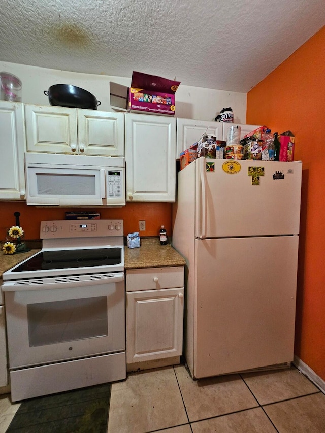 kitchen featuring white appliances, light tile patterned floors, white cabinetry, and a textured ceiling