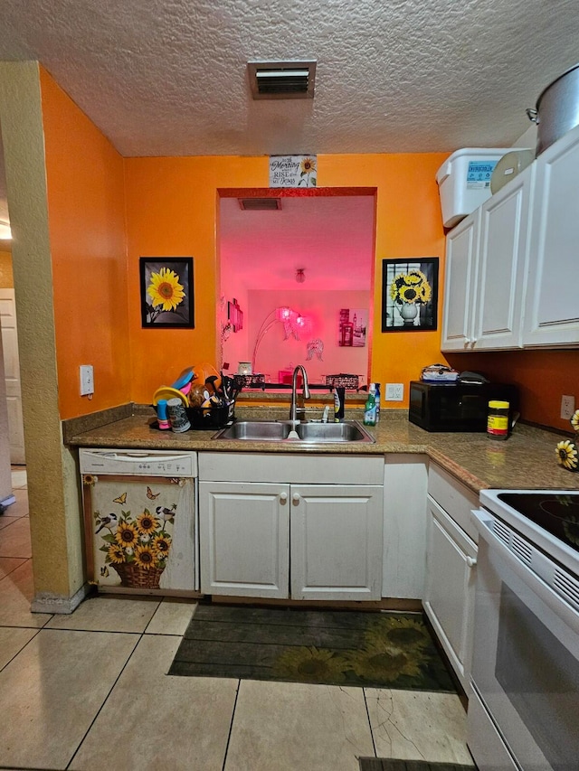 kitchen featuring a textured ceiling, white appliances, sink, tile patterned floors, and white cabinetry