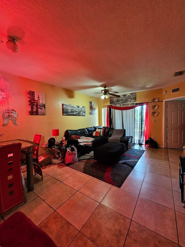 living room with ceiling fan, a textured ceiling, and tile patterned floors