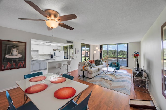 dining space with a textured ceiling, light hardwood / wood-style flooring, ceiling fan, and sink