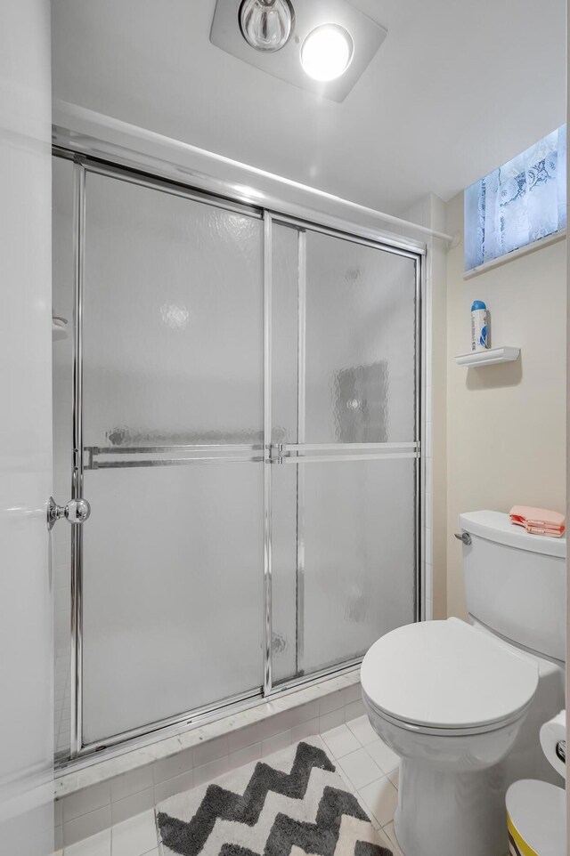 bathroom featuring tile patterned flooring, toilet, and walk in shower