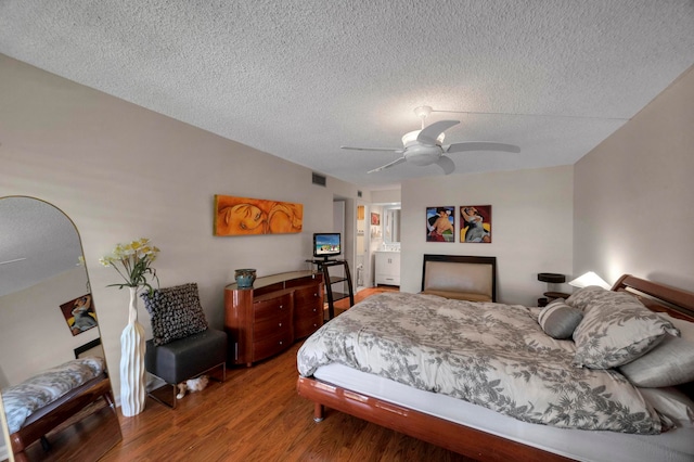 bedroom with a textured ceiling, hardwood / wood-style floors, and ceiling fan