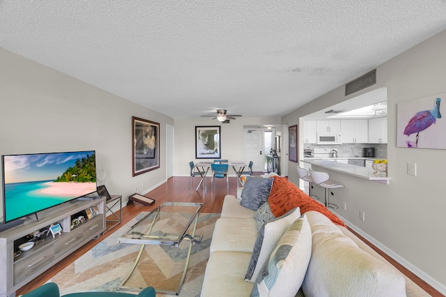 living room with wood-type flooring, a textured ceiling, and ceiling fan