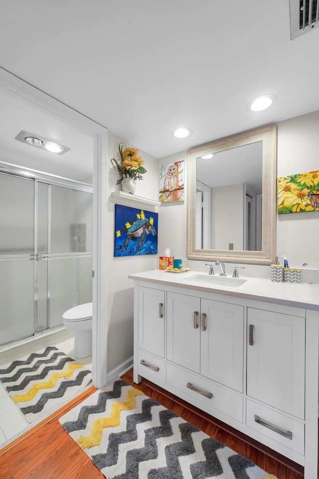 bathroom with walk in shower, vanity, toilet, and hardwood / wood-style floors