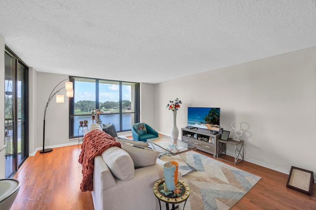 living room featuring a textured ceiling, wood-type flooring, and floor to ceiling windows