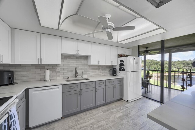 kitchen with backsplash, gray cabinetry, white appliances, sink, and ceiling fan