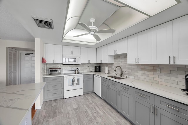 kitchen featuring gray cabinets, light hardwood / wood-style floors, white appliances, and tasteful backsplash