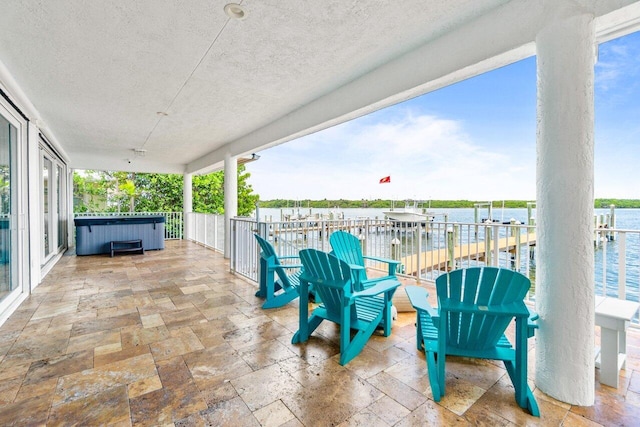 view of patio / terrace featuring a water view and a hot tub