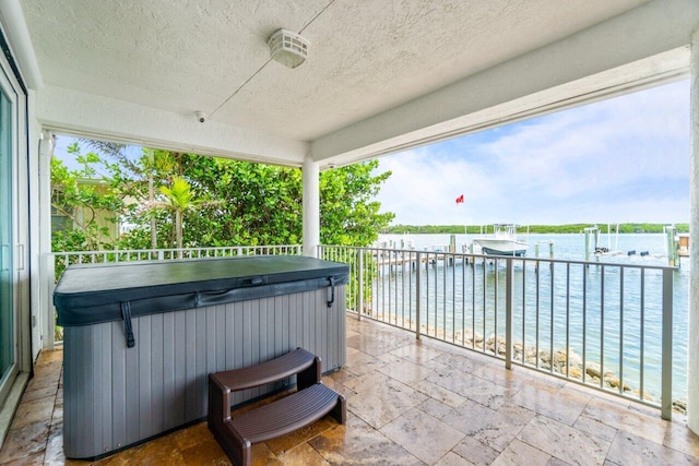 view of patio / terrace featuring a dock, a water view, and a hot tub