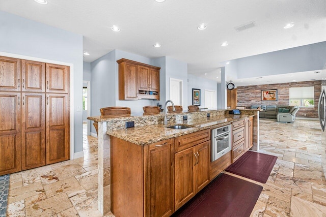 kitchen with stainless steel oven, sink, plenty of natural light, and a breakfast bar area