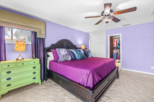 carpeted bedroom featuring ceiling fan, a textured ceiling, a closet, and a walk in closet