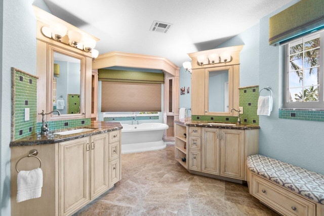 bathroom with backsplash, a bath, and vanity