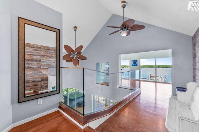 hall featuring a water view, hardwood / wood-style floors, and high vaulted ceiling