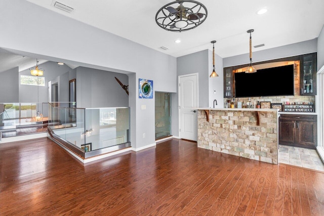 interior space featuring ceiling fan, dark wood-type flooring, hanging light fixtures, and vaulted ceiling