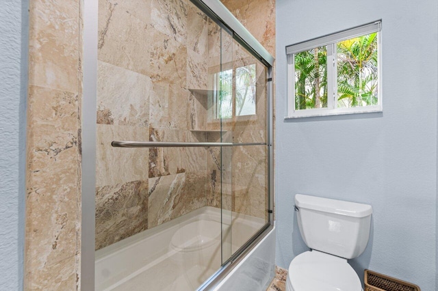 bathroom featuring bath / shower combo with glass door and toilet