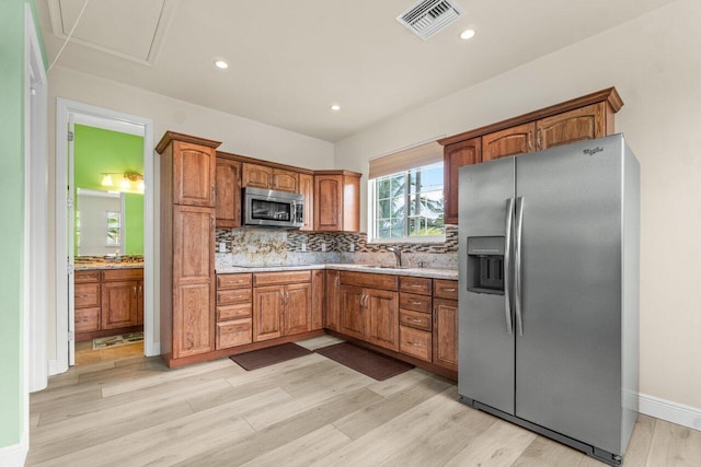 kitchen with light wood-type flooring, backsplash, appliances with stainless steel finishes, and sink