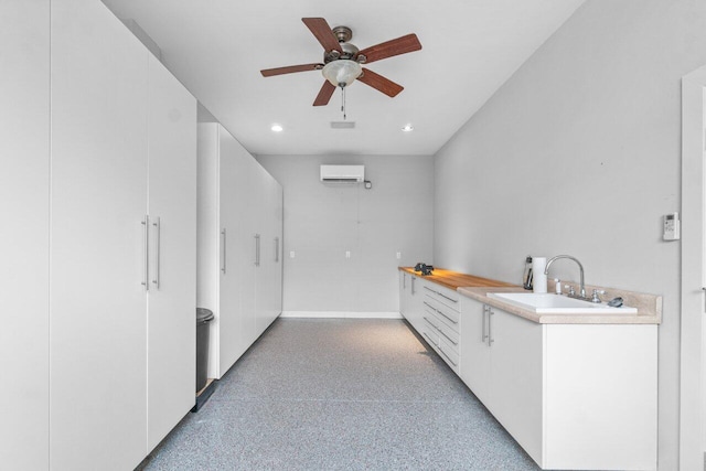 kitchen featuring ceiling fan, sink, white cabinetry, and an AC wall unit