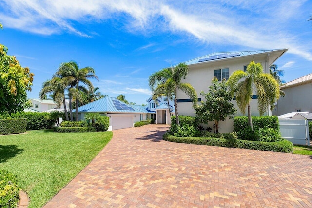 view of front of house featuring solar panels, a front yard, and a garage