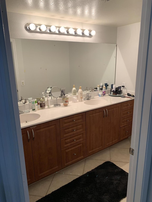 full bathroom featuring a sink, a textured ceiling, double vanity, and tile patterned floors