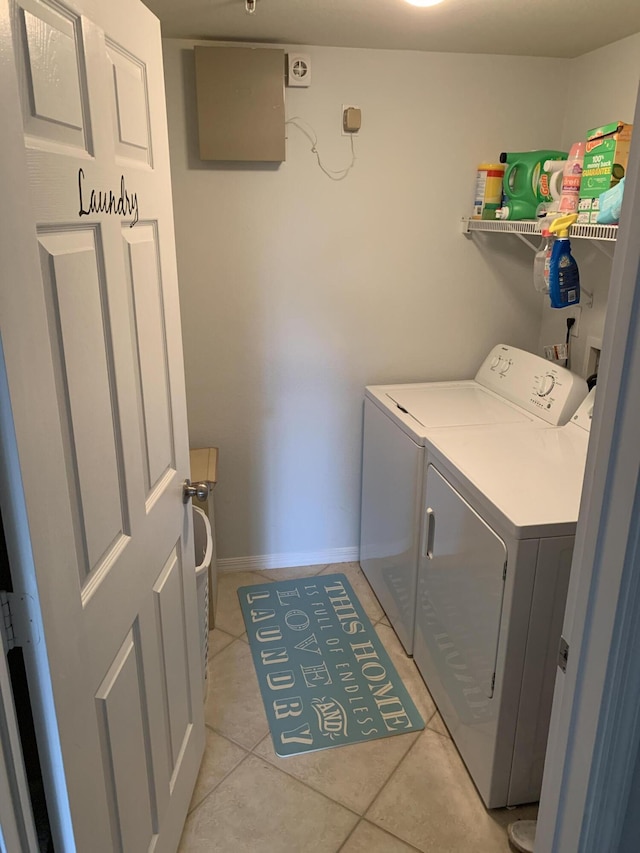 clothes washing area with light tile patterned floors, laundry area, independent washer and dryer, and baseboards