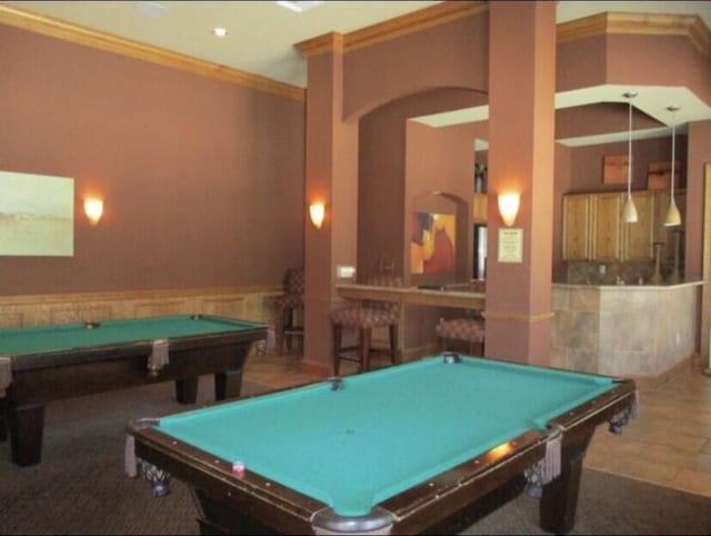 playroom featuring billiards, a wainscoted wall, arched walkways, ornamental molding, and a bar