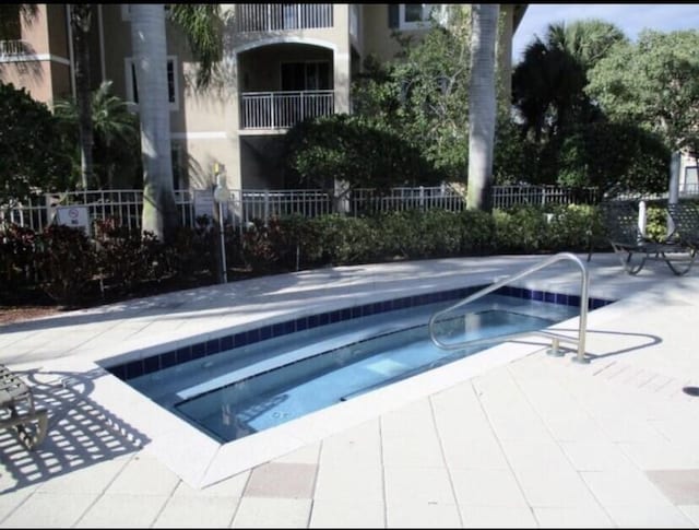 view of swimming pool with a patio area, fence, and a hot tub