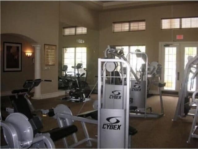 exercise room featuring arched walkways, a healthy amount of sunlight, and ornate columns