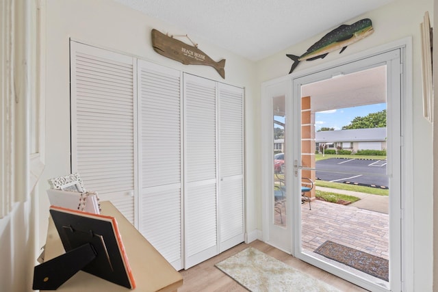 doorway to outside with a textured ceiling and wood finished floors