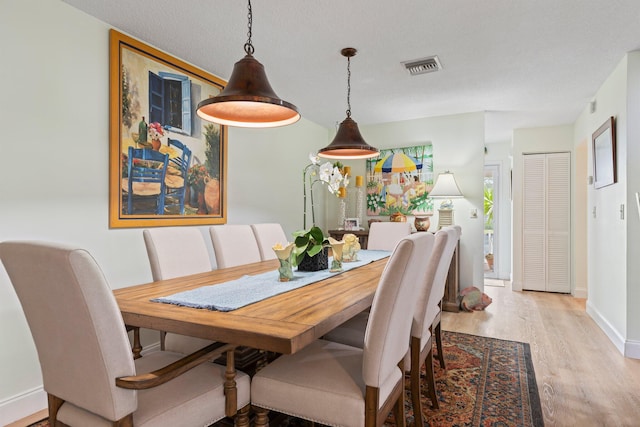 dining room featuring light hardwood / wood-style floors and a textured ceiling