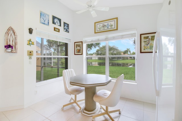 dining space with a water view, ceiling fan, and light tile patterned flooring