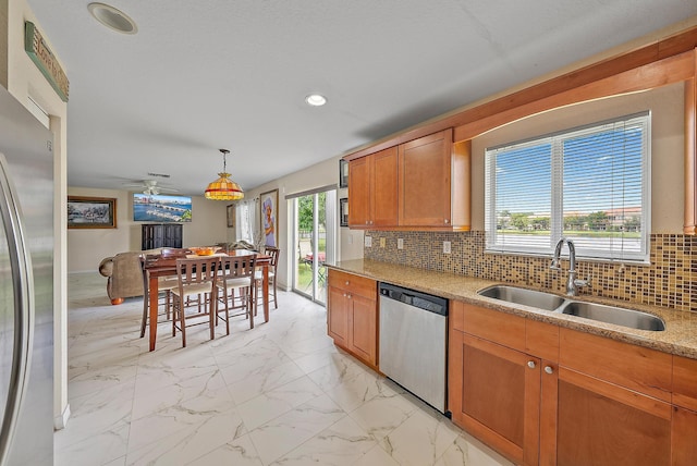 kitchen featuring light stone countertops, light tile patterned floors, backsplash, appliances with stainless steel finishes, and sink