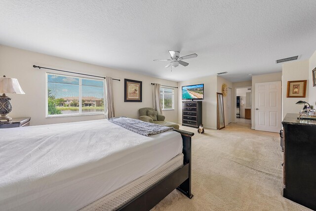 bedroom with ceiling fan, light carpet, and a textured ceiling