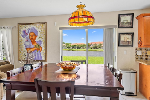 dining space featuring a water view and light tile patterned floors