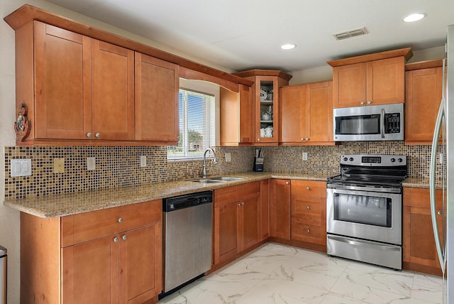 kitchen featuring appliances with stainless steel finishes, light stone counters, light tile patterned floors, and decorative backsplash