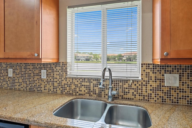 kitchen featuring light stone counters, backsplash, and sink