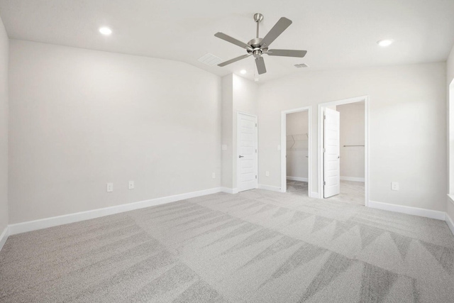 unfurnished bedroom with ceiling fan, lofted ceiling, a walk in closet, light carpet, and a closet