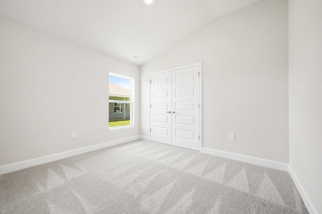 unfurnished bedroom featuring a closet, carpet, and lofted ceiling