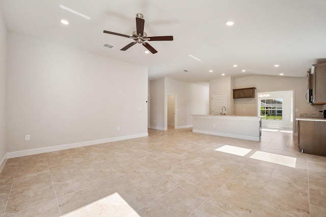 unfurnished living room featuring light tile patterned floors, vaulted ceiling, ceiling fan, and sink