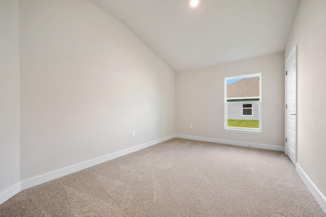 carpeted empty room with vaulted ceiling