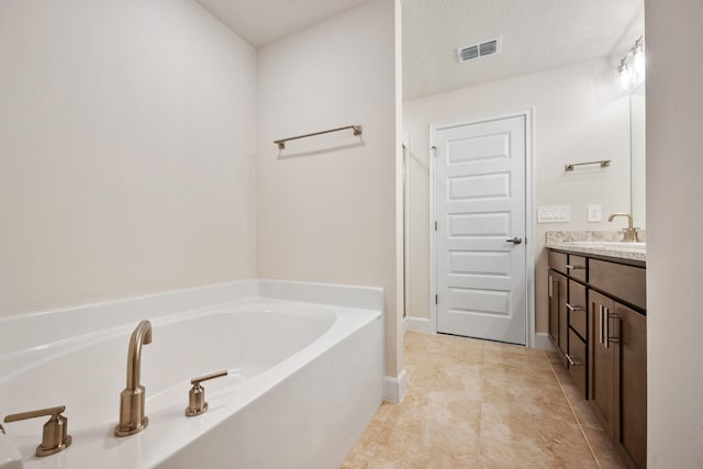 bathroom featuring tile patterned floors, vanity, a bathtub, and a textured ceiling