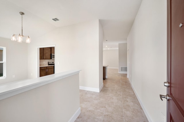 hall with an inviting chandelier, lofted ceiling, and light tile patterned flooring