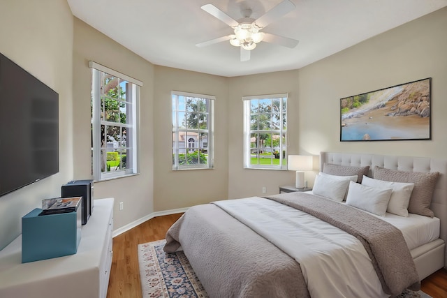 bedroom with hardwood / wood-style flooring, ceiling fan, and multiple windows