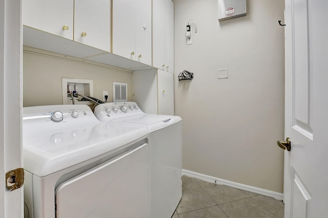 clothes washing area featuring washing machine and dryer, light tile patterned floors, and cabinets