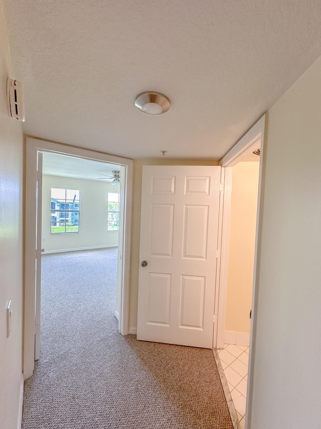 hallway featuring light carpet and a textured ceiling