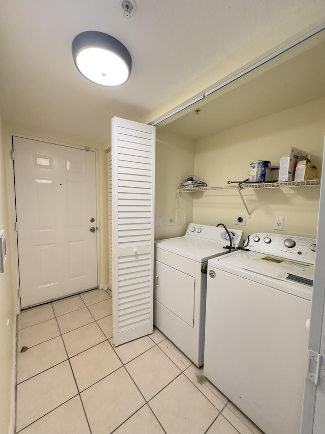 laundry area with washer and clothes dryer and light tile patterned floors