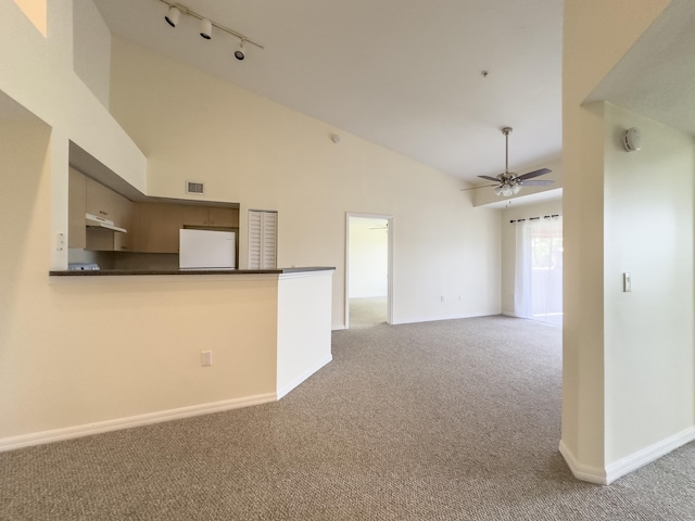 kitchen with white fridge, rail lighting, kitchen peninsula, ceiling fan, and carpet flooring