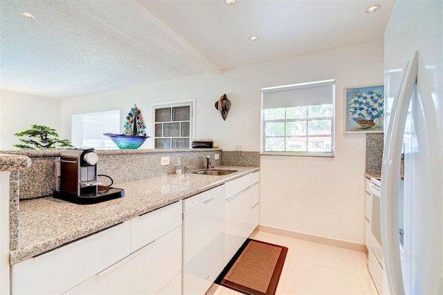 kitchen with light stone counters, recessed lighting, white cabinetry, a sink, and white appliances