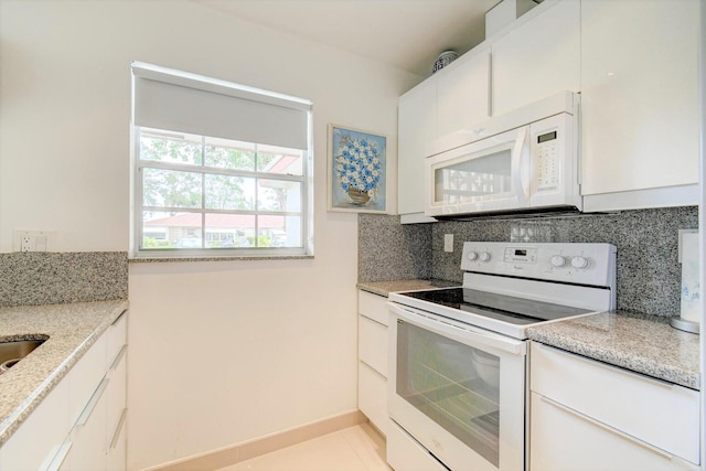 kitchen featuring white appliances, light stone counters, backsplash, and white cabinetry